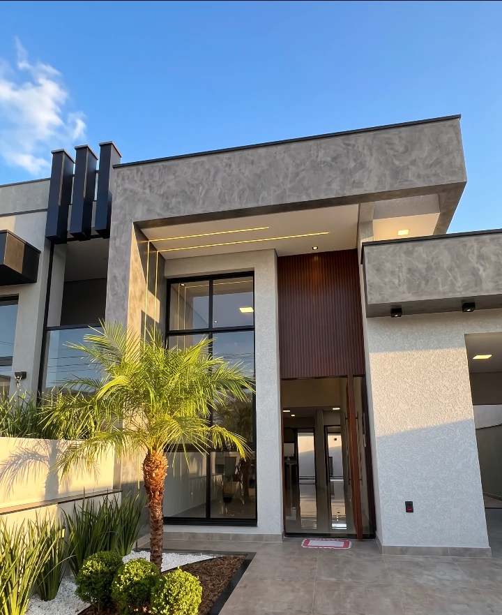 Fachada diurna da casa nova, com jardim e revestimento moderno